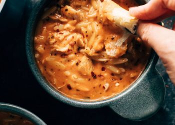 White hand dipping bread into soup