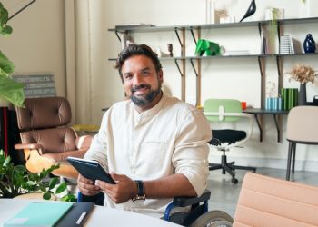 man in a wheelchair holding a computer tablet