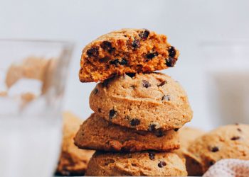 Stack of vegan gluten-free pumpkin chocolate chip cookies with the top one broken apart to show the texture