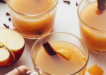 Hand holding a glass mug filled with homemade spiced apple cider