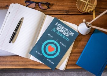 a book and a notebook with pen on a table