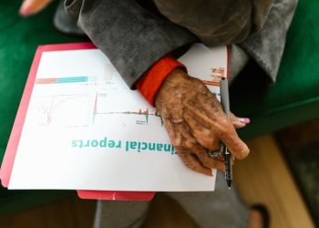 Person holding pen and looking at financial projections on paper