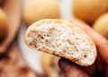 Hand holding up a vegan gluten-free dinner roll to show the inner texture
