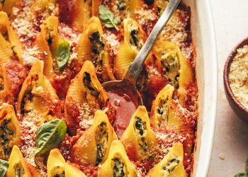 Spoon in a baking dish of vegan stuffed shells