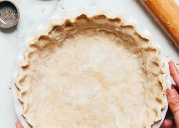 Hands holding the sides of a pie pan filled with vegan gluten-free pie crust