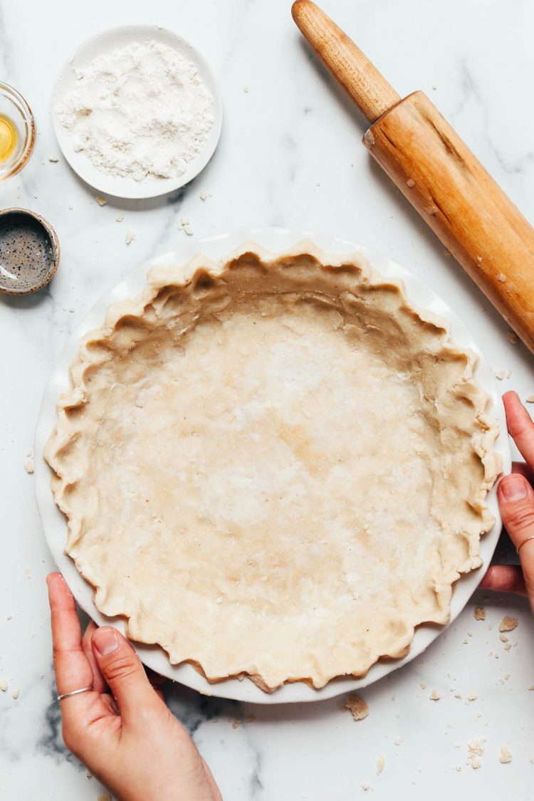 Hands holding the sides of a pie pan filled with vegan gluten-free pie crust