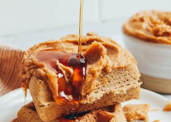 Drizzling maple syrup onto a stack of waffles
