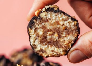 Holding a snickers energy bite between two fingers to show the inner texture